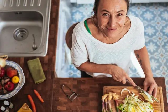 A woman cooking and looking up at the camera