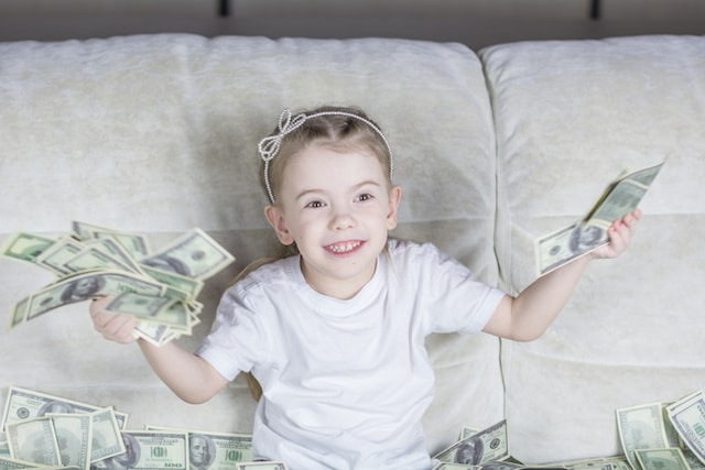 Little girl holding a bunch of dollar bills.