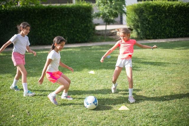 Three girls playing football outside.