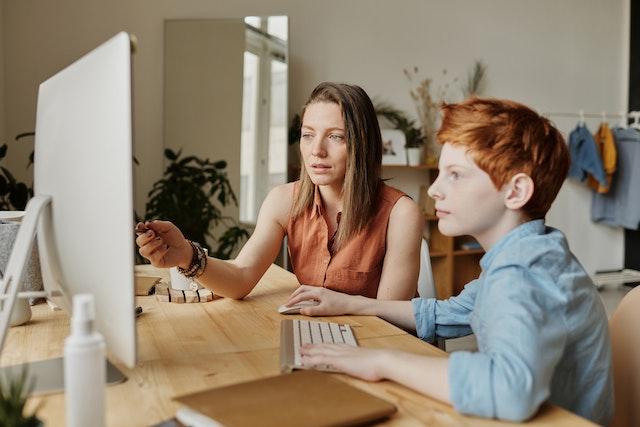 A mother introducing her son to educational apps and content on a computer.
