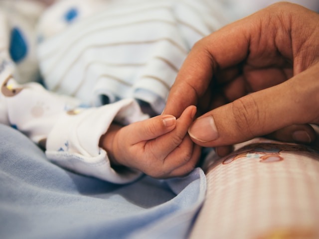 Close-up of a person holding a baby’s hand